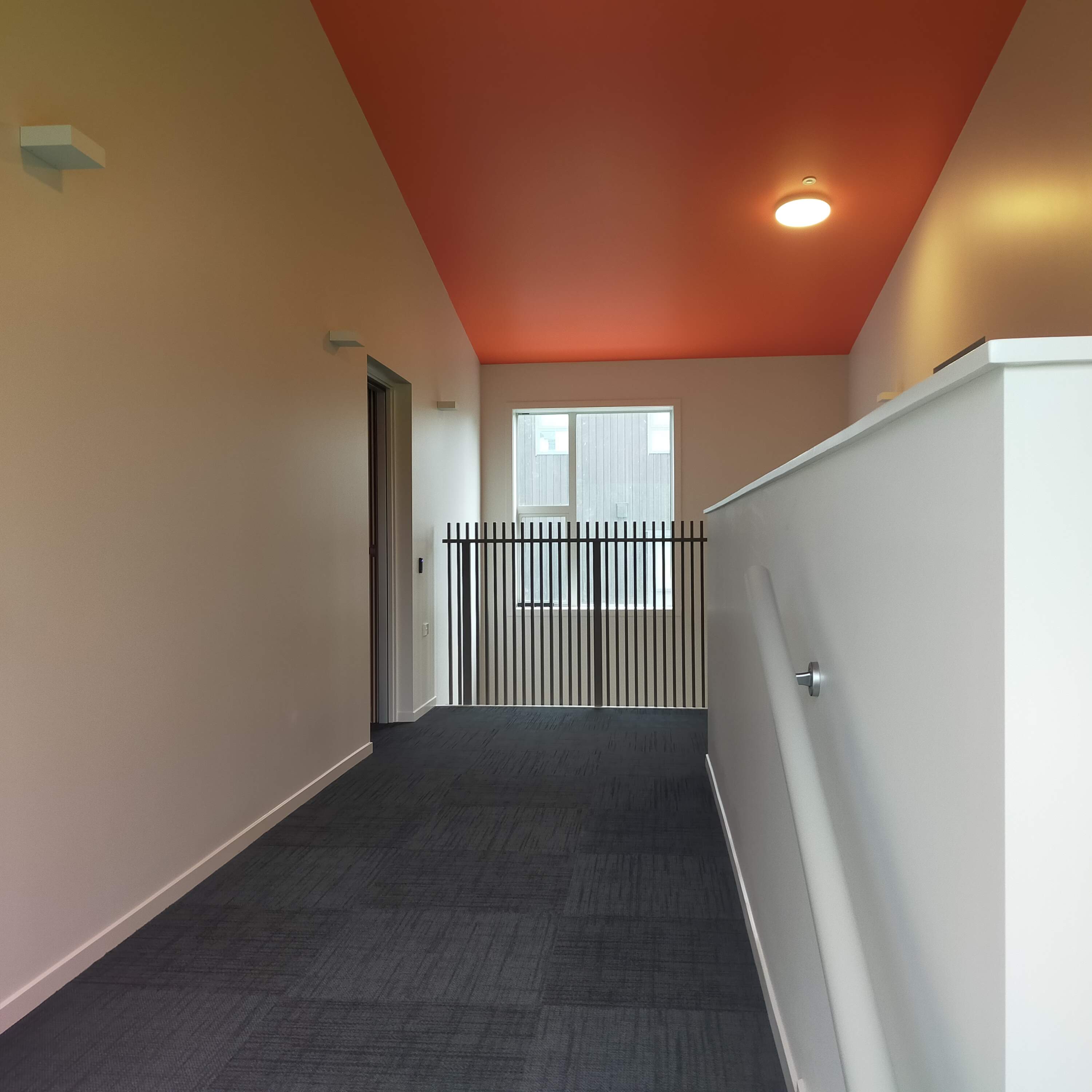 Commercial hallway - orange accent ceiling with metal balustrade
