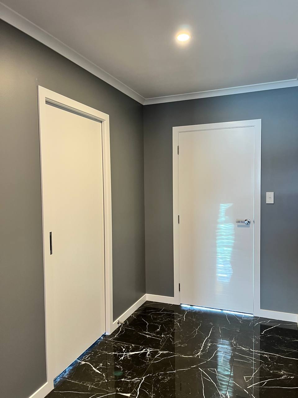 Modern hallway - grey accent walls with dark marble-look tile flooring