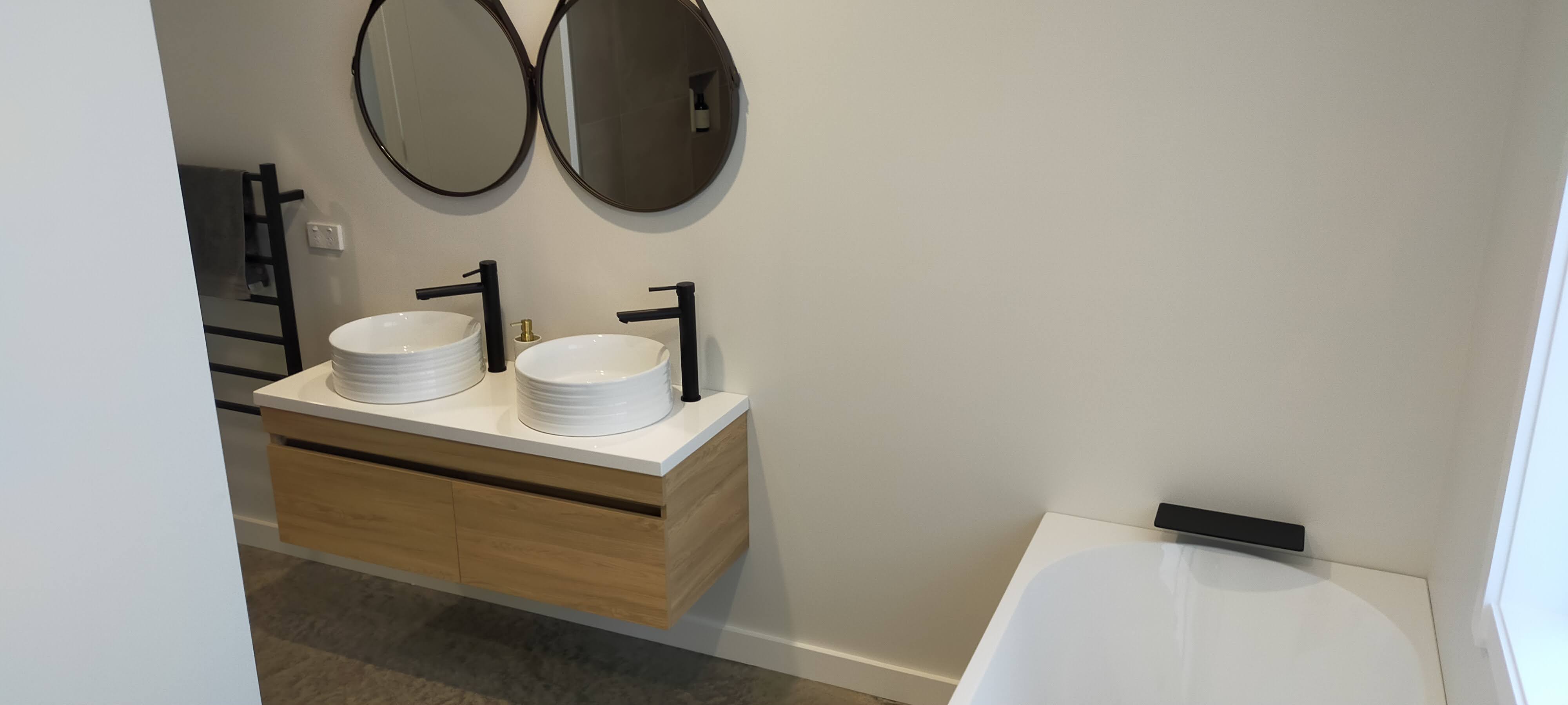Modern bathroom - double vessel basins with black fixtures and round mirrors