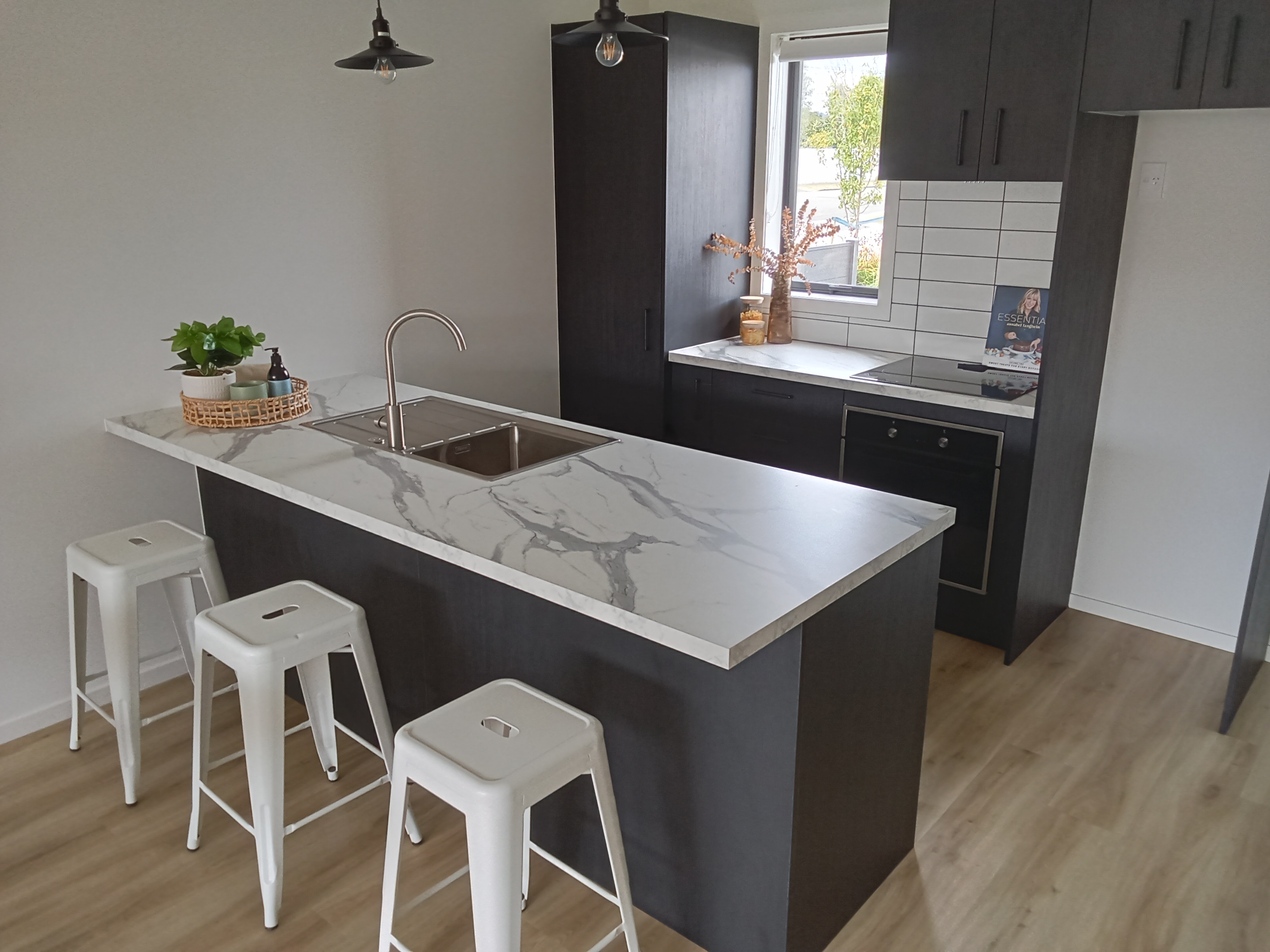 Modern kitchen - dark cabinets with marble benchtop and white subway tile splashback