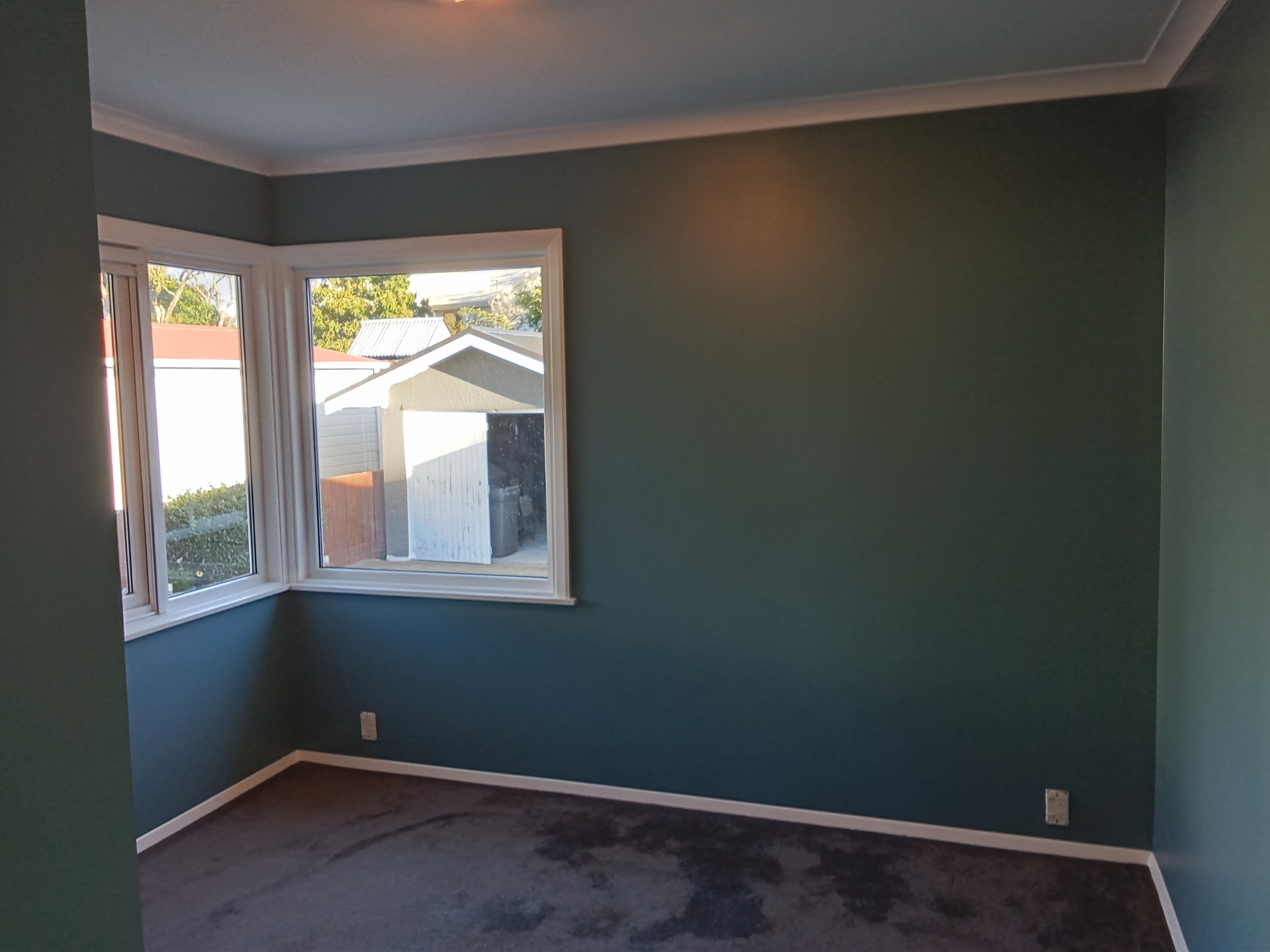 Teal feature wall bedroom with bay window - crisp white trims and skirting