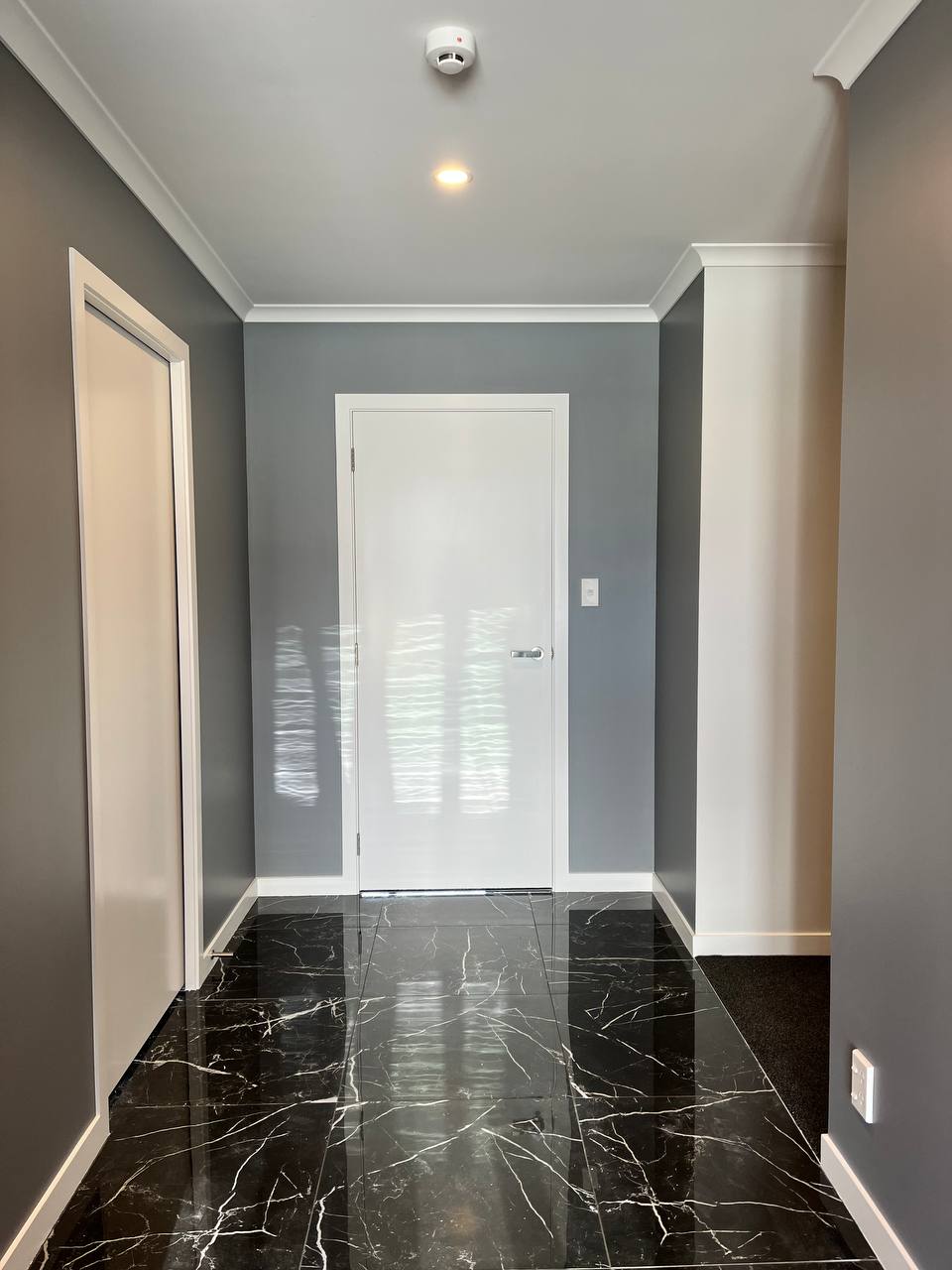 Hallway detail - grey walls with gloss white door and marble floor
