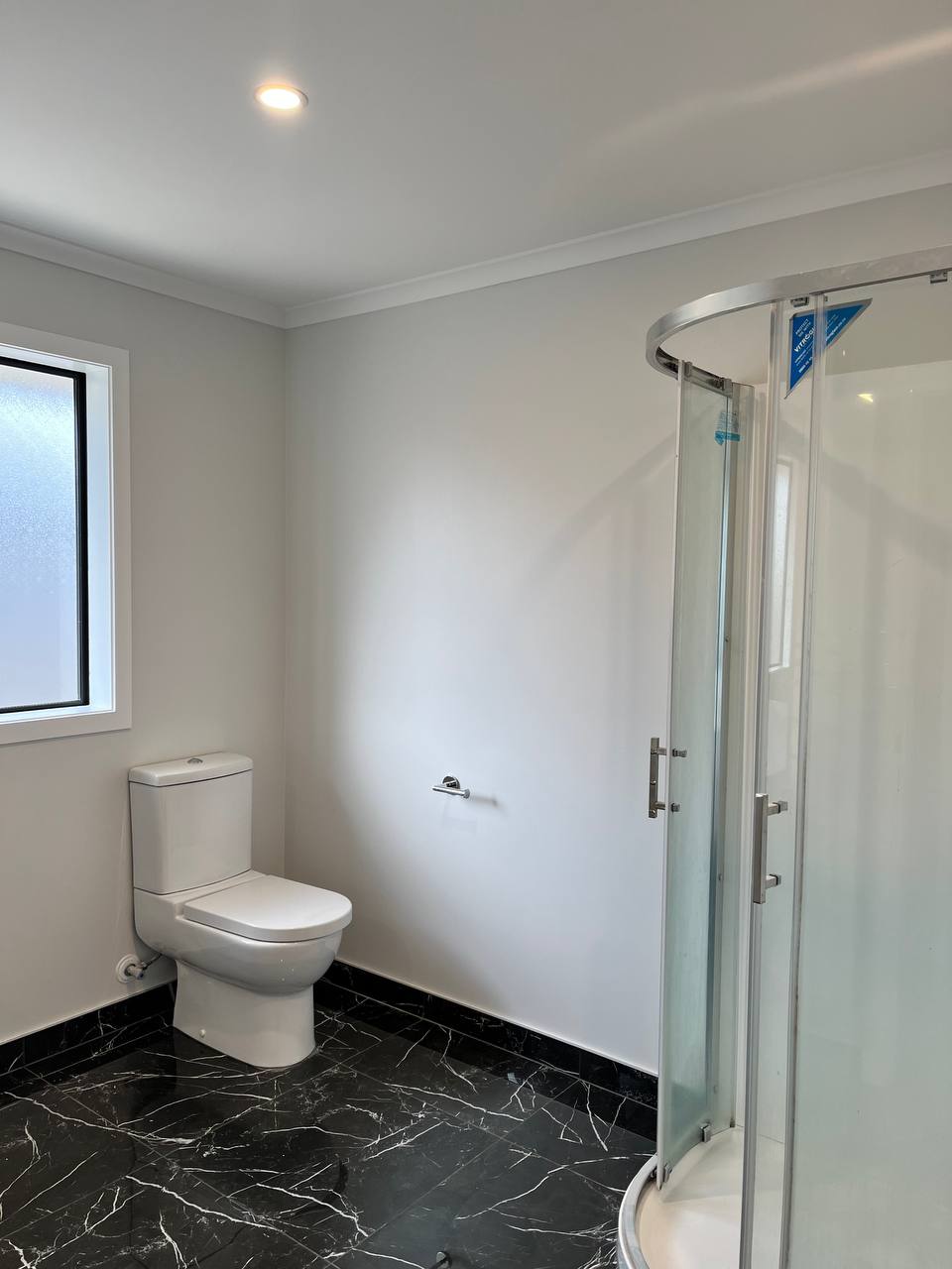 Bathroom - grey walls with marble floor and curved glass shower